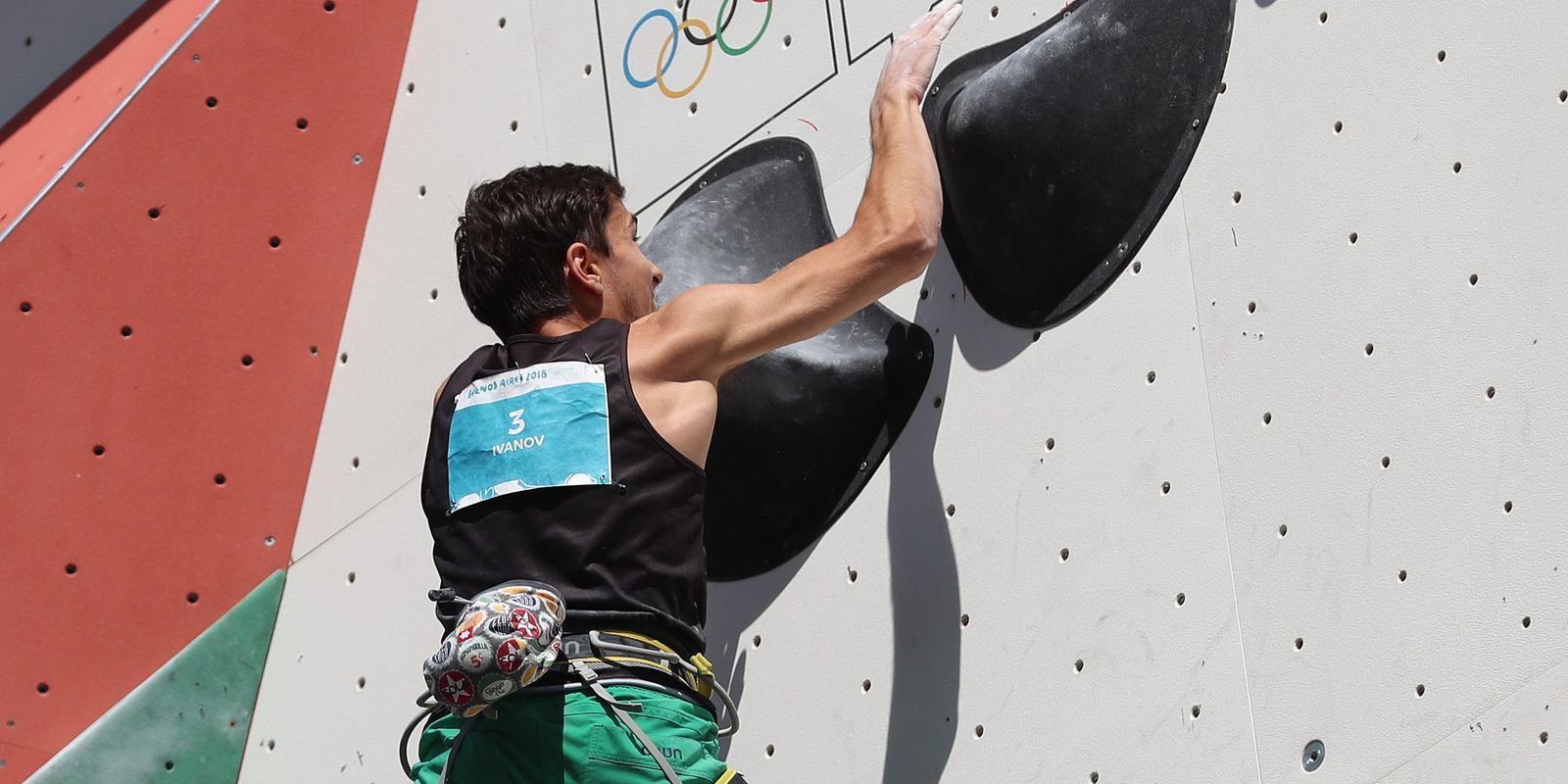 A young climber gripping holds on a competition boulder wall
