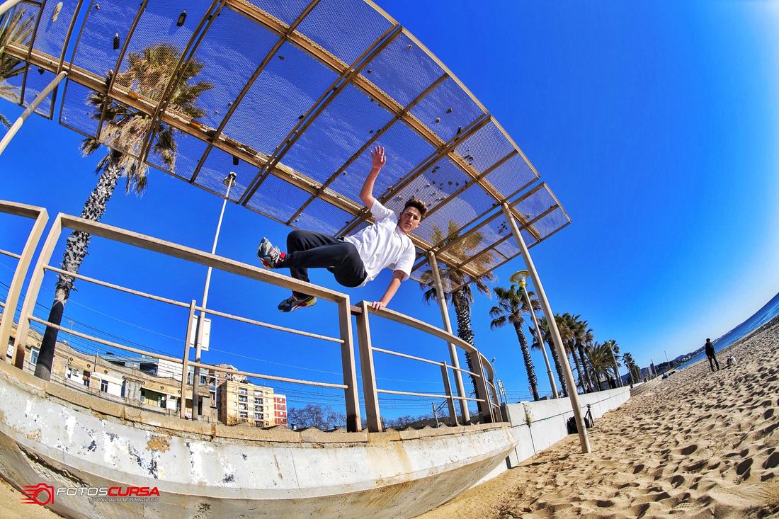 A traceur vaulting over a barrier on a sunny promenade