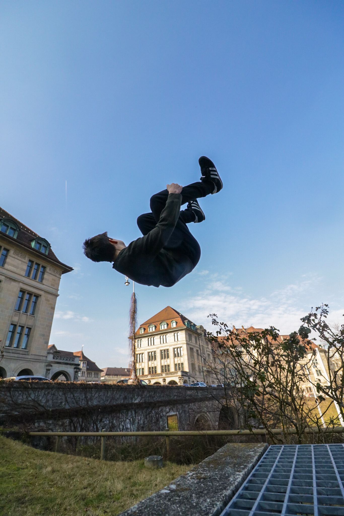 A trained freerunner performing a sideflip above concrete in Zurich