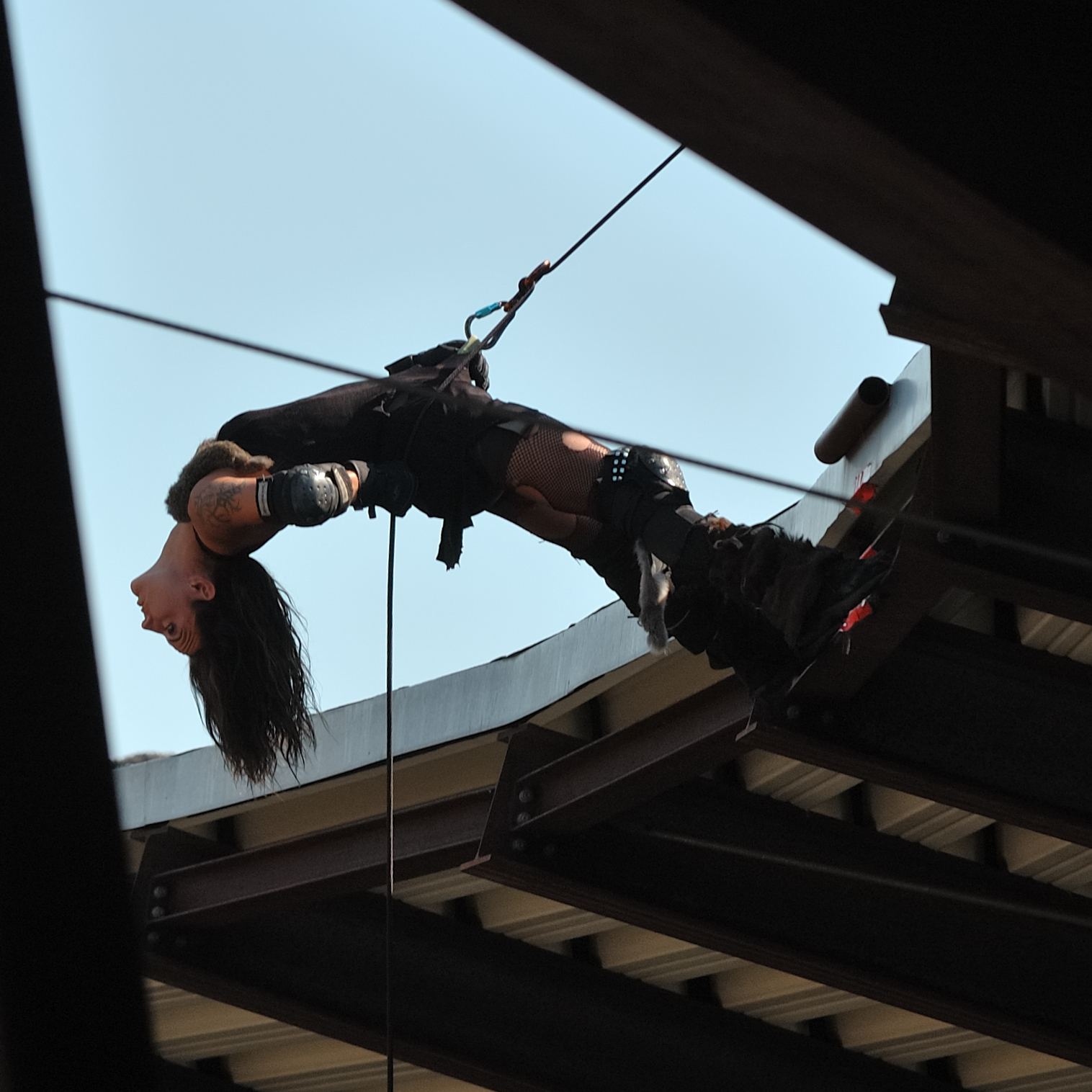 A stuntwoman hanging in a harness high above a stunt show arena